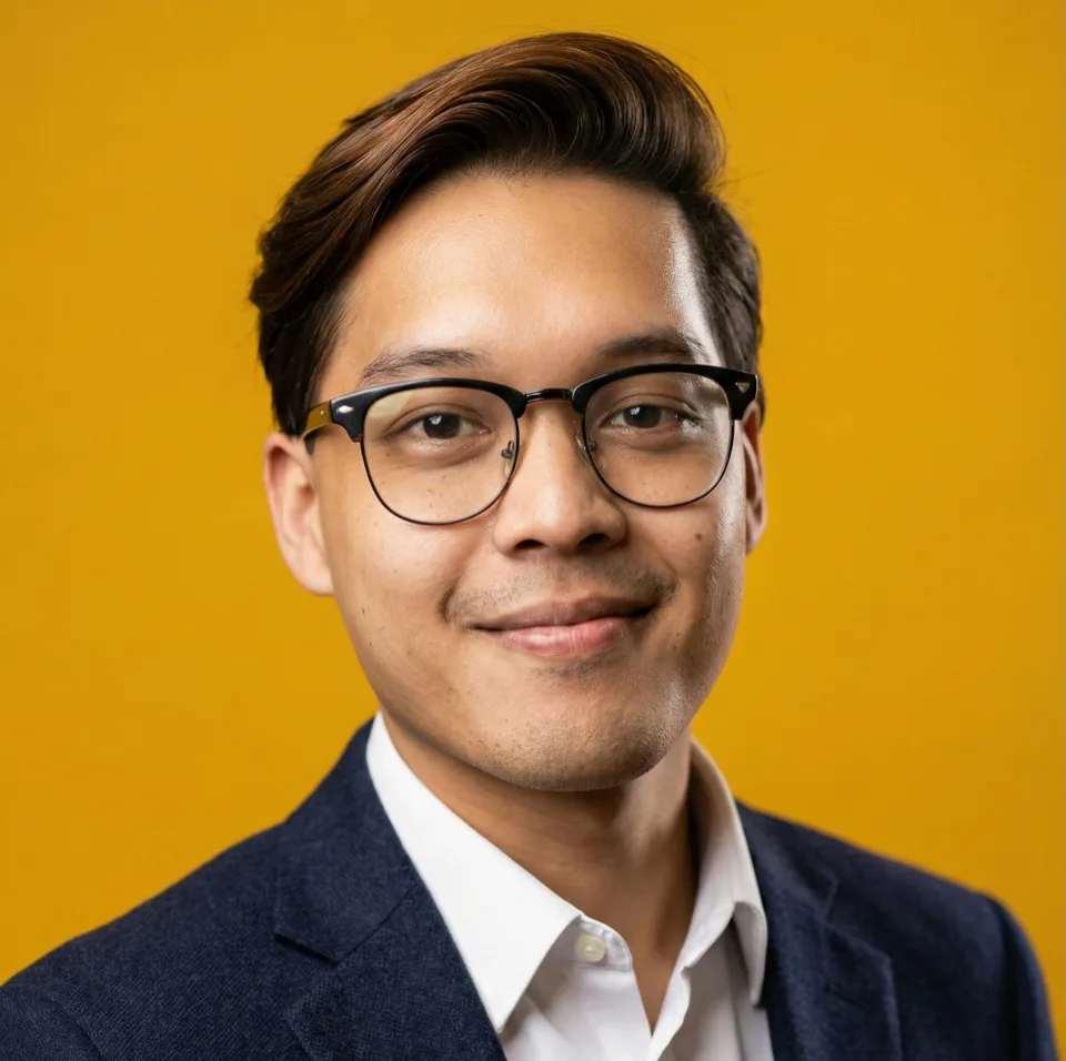 Syafie Mustafa, founder of Hexa Partners, smiling in glasses and a navy blazer against an amber background